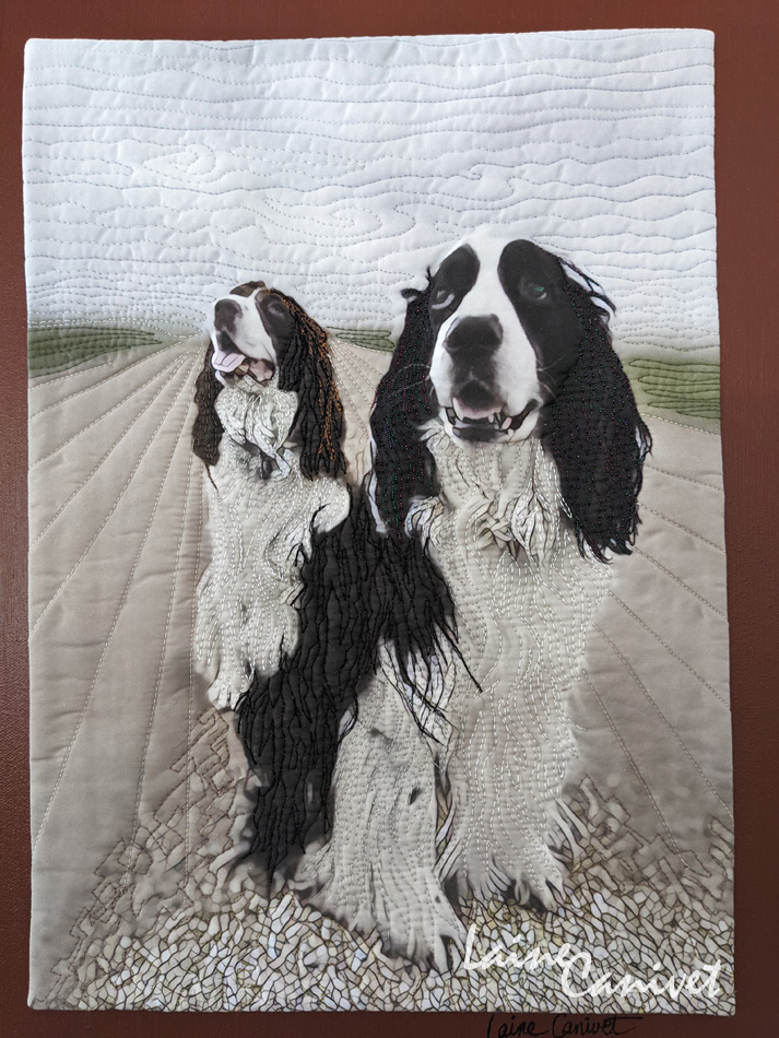 a fabric quilt depicting two black and white dogs looking at the camera